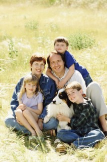 Family and their dog sitting in meadow together. Photo : Rob Lewine