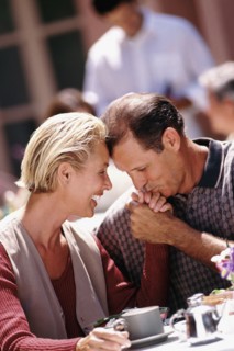 Man kissing woman's hand while sitting at patio table. Photo : Rob Lewine