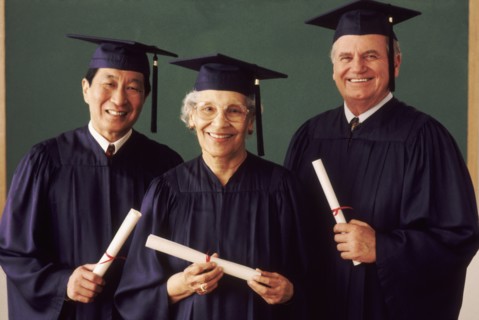 Three adult students wearing graduation gowns. Photo : Rob Lewine