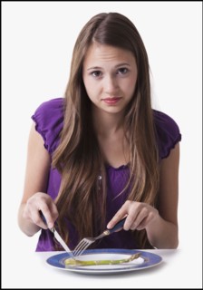 Unsatisfied teenage girl cutting a spear of asparagus. Photo : Mike Kemp