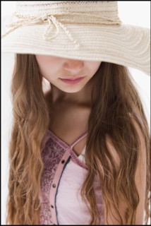 Long haired woman wearing a straw hat that covers her eyes. Photo : Mike Kemp