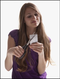 Woman cutting up a credit card. Photo : Mike Kemp
