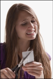 Woman reluctantly cutting her credit card. Photo : Mike Kemp