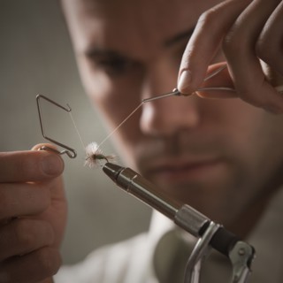 Man repairing fly fishing hook. Photo : Mike Kemp