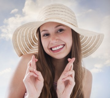Woman wearing a straw hat and crossing her fingers. Photo : Mike Kemp