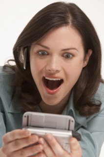 Surprised woman looking at hand held device. Photo : K.Hatt