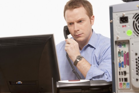 Businessman talking on phone while looking at computer. Photo : K.Hatt