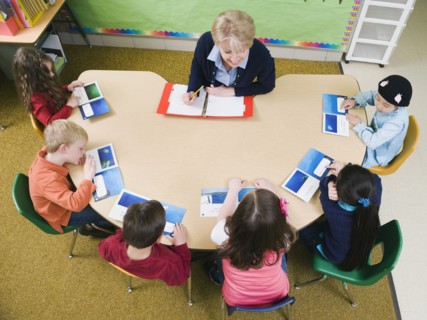 Kindergarten students sitting at table with their teacher.