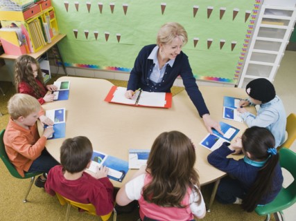 Kindergarten students sitting at table with their teacher.