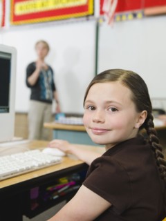 Elementary student sitting at desk in classroom.