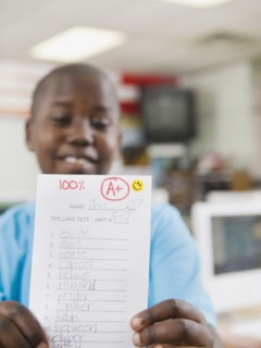 Elementary student holding an A grade paper.