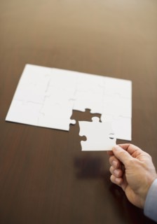 Hand putting last puzzle piece in puzzle.