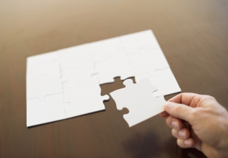 Hand putting last puzzle piece in puzzle.
