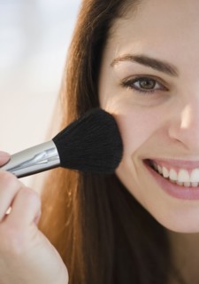 Young woman putting on blush. Photo : Jamie Grill