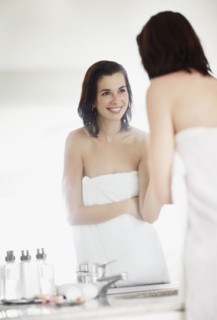 Woman looking at her reflection in mirror. Photo : momentimages