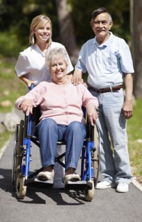 Nurse pushing senior woman in a wheelchair. Photo : momentimages