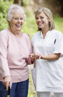 Nurse assisting senior walking with a cane. Photo : momentimages