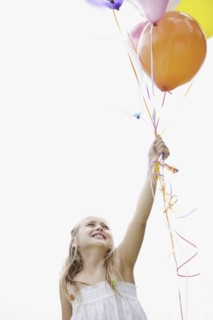 Young girl holding balloons. Photo : momentimages