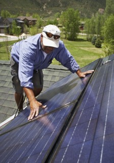 Construction worker installing solar panel on roof. Photo. Shawn O'Connor