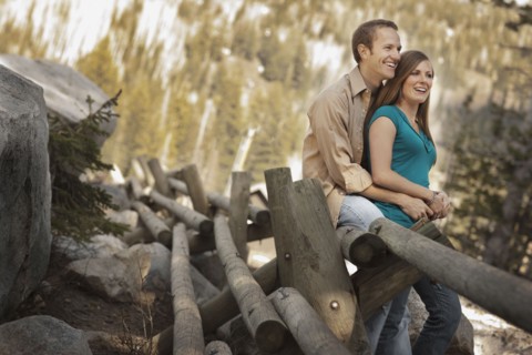 Happy couple sitting on log fence. Photo : FBP