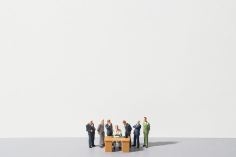 Figurines of people standing around desk. Photo : Antonio M. Rosario