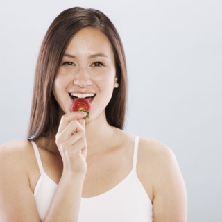 Brunette woman eating a strawberry. Photo. FBP