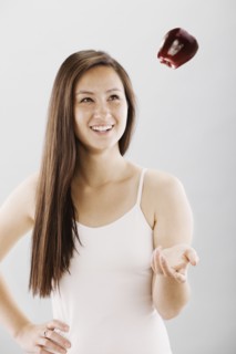Woman tossing a red apple. Photo. FBP