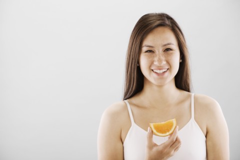 Woman holding a slice of orange. Photo. FBP