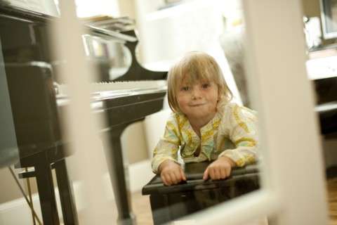 Young girl lying on piano bench. Photo : Tim Pannell