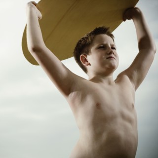 Young boy holding a surfboard over his head. Photo : FBP