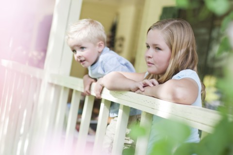 Brother and sister gazing over porch railing. Photo : Tim Pannell