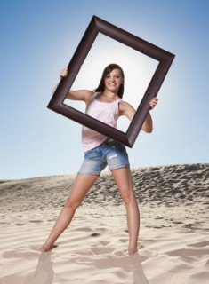 Woman standing on beach holding picture frame. Photo. Mike Kemp