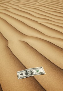 100 dollar bill on sand in desert. Photo : Mike Kemp
