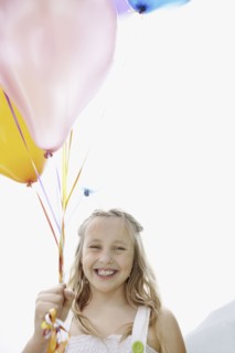 Young girl holding balloons. Photo : momentimages