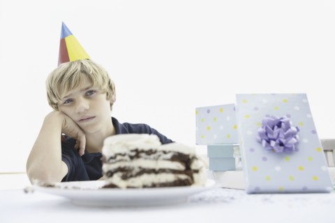 Tired young boy at a birthday party. Photo : momentimages