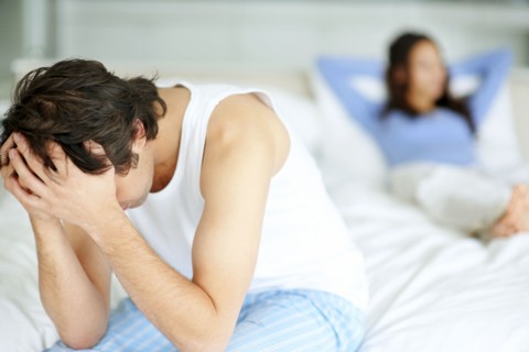 Frustrated man sitting on edge of bed. Photo : momentimages