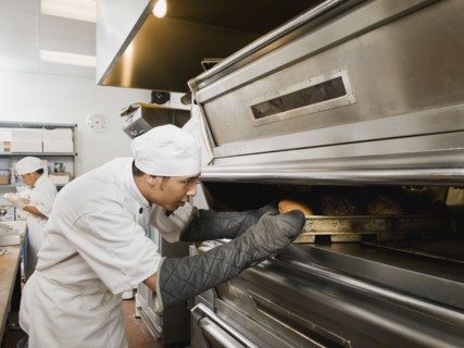 Chef putting bread in oven.