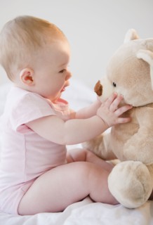 Baby playing with teddy bear. Photo : Jamie Grill
