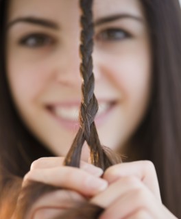 Young woman braiding her hair. Photo : Jamie Grill