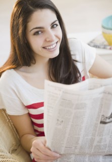 Brunette woman reading the newspaper. Photo : Jamie Grill