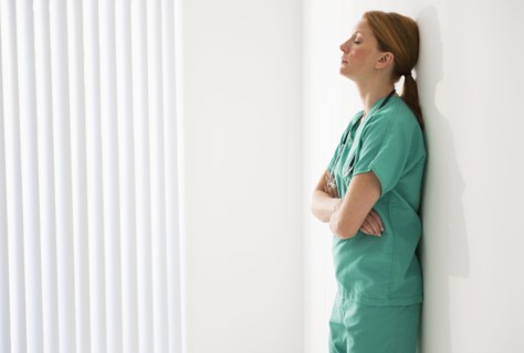Tired doctor leaning against wall.