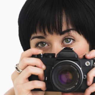 Woman holding a camera. Photo : Daniel Grill