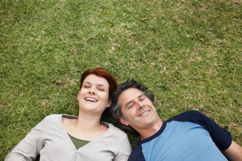 Happy couple relaxing on the grass together. Photo : momentimages