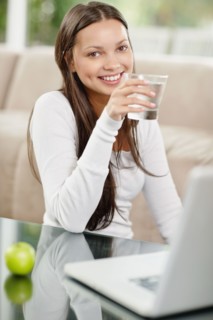 Woman drinking water while browsing the internet. Photo : momentimages