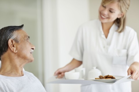 Nurse giving tray of food to patient. Photo : momentimages