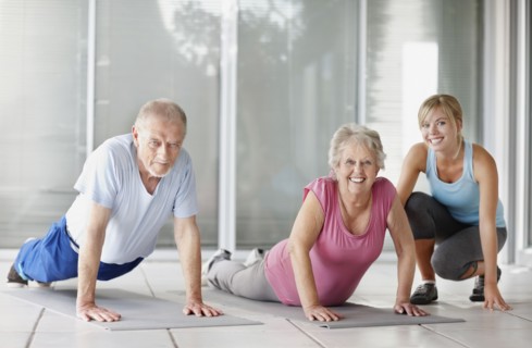Senior couple exercising with a fitness instructor. Photo. momentimages