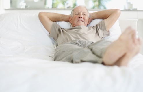 Relaxed senior man lying on bed. Photo. momentimages