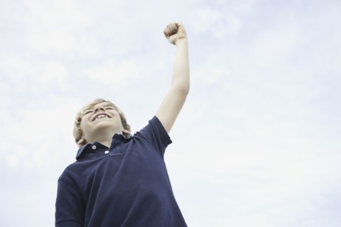 Young boy with his arm raised. Photo : momentimages