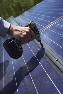 Construction worker installing solar panel on roof. Photo : Shawn O'Connor
