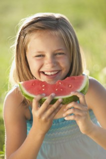 Young girl eating a slice of watermelon. Photo : Mike Kemp